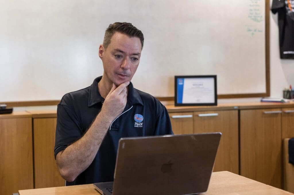 Dive centre manager reviewing a Divemaster job application on a laptop